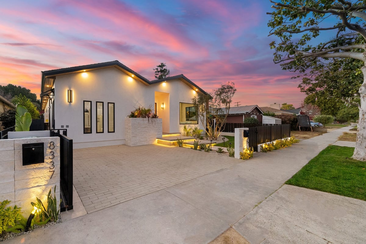 Home with illuminated front yard at sunset