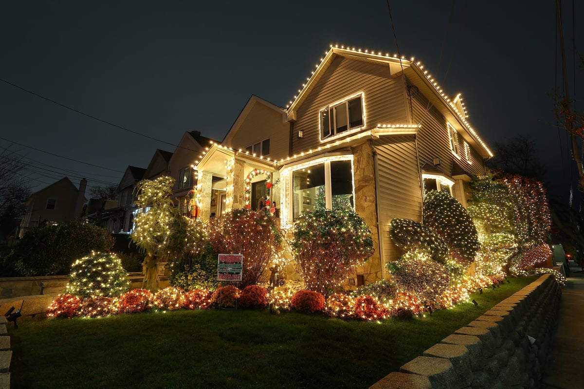 Luxury South Florida home at twilight with warm white roofline and palm tree holiday lighting